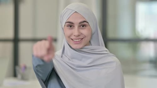 Smiling Woman in Hijab Points Forward