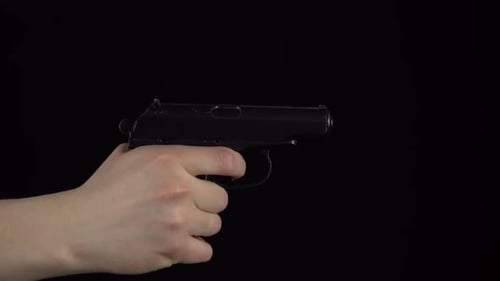 A Man Makes a Shot From a Pistol. Pistol in Hand Close-up Slow Motion Makes a Shot. On a Black