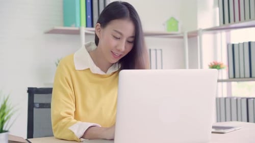 Asia business woman writing notebook document finance and calculator in home office.