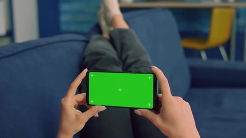 Woman Holding Smartphone with Green Screen on Couch