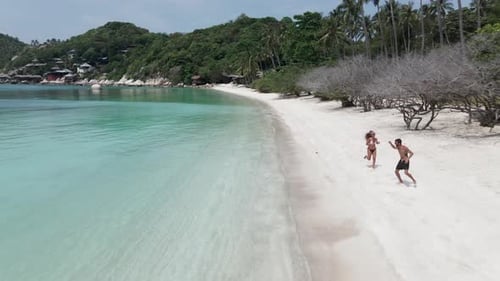 A Drone Shot of a Happy Cheerful Couple Having Fun Running to the Sea Together on a Tropical Beach