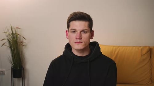 Young Adult Man in Hoodie Sitting Indoors