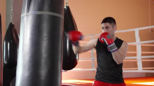 Man Punches Punching Bag in Gym