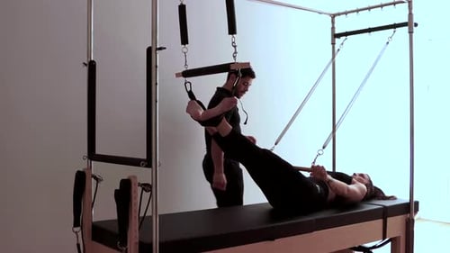 Woman Doing Pilates Reformer Workout with Instructor