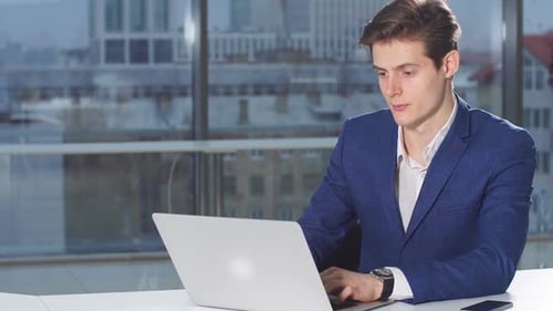 Portrait of Modern Attractive Businessman Working at Desk in Office Using Laptop