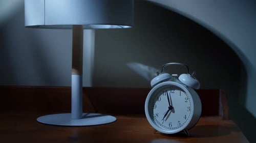 Hand Turns off White Alarm Clock at Night