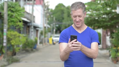 Man Using Phone on Quiet Residential Street