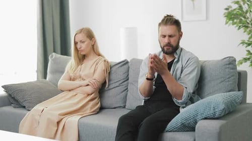 Upset Couple Sitting on Opposite Ends of Couch
