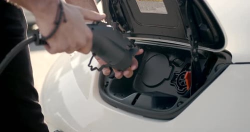 Young Arab Man Recharging White Electric Car at Parking Lot