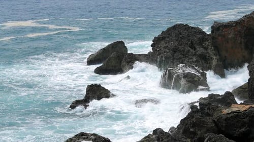 Breaking waves beating and rolling stones at sea coast