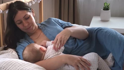 Mother Breastfeeding Baby at Home on Bed