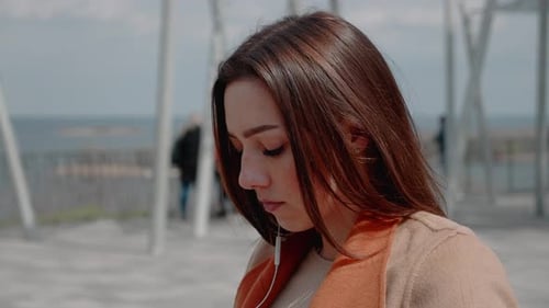 Woman Puts on an Earphone and Listens to Music on the Outdoor Terrace