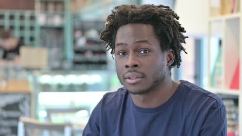 Porträt eines afrikanischen Mannes, der der Kamera zuwinkt