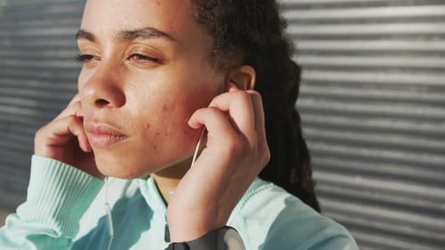 Young Woman Puts in Earphones Before a Run