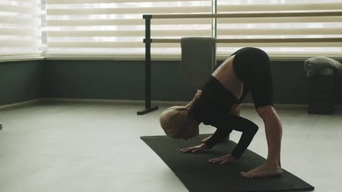 Woman Practicing Yoga on Mat in Studio