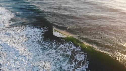 Surfers Riding Waves in Golden Hour from Above
