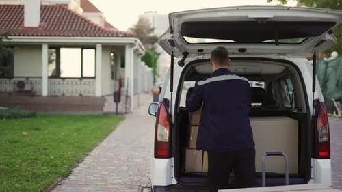 Young Handsome Caucasian Delivery Man Putting Boxes in Van Delivering Shipment