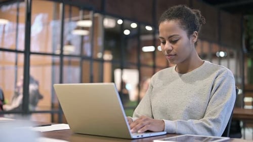 Woman Typing on Laptop in Urban Office