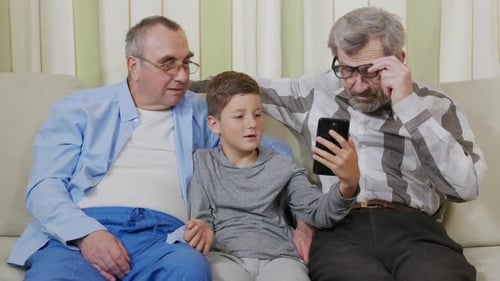 Grandfathers and Grandson Using Smartphone Together at Home