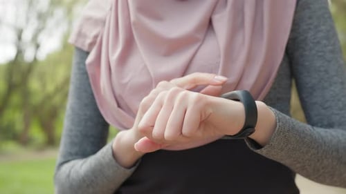 Woman Uses Smart Watch in Urban Park Setting