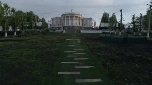 Aerial view of beautiful house of culture, square and alley. The camera flies low down the alley 19