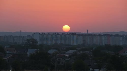 Evening Landscape with Bright Setting Sun Over Distant City High Rise Buildings at Sunset