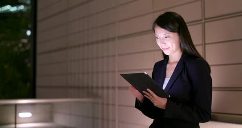 Woman Using Tablet at Night in City