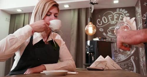 Kellnerin trinkt Kaffee und benutzt eine Papierserviette
