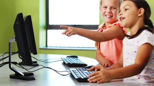 Smiling Girls Learning on Computers in Classroom