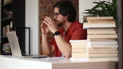 Stylish man sitting at table in home office and using laptop