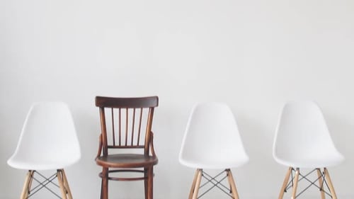 Wooden Chair Among Modern Chairs in a Minimalist Setting