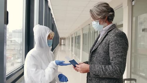 Airport Worker in Protective Equipment Checking Mans Passport and Boarding Pass