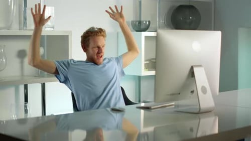 Man Celebrates Success at Computer in Modern Office