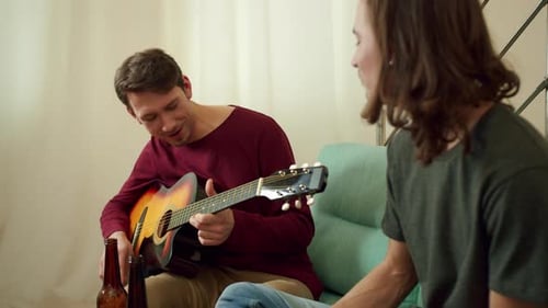 Young Man Playing Guitar with Friend Indoors