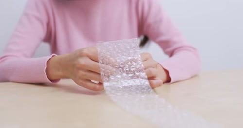 Person Pops Bubble Wrap At Table In Home