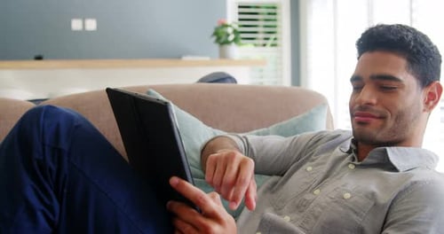 Young Adult Using Tablet on Couch Indoors