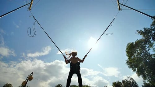 Young Girl Jumps on Bungee Trampoline on Sunny Day