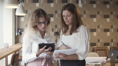 Two Women Coworkers Looking at Tablet in Office