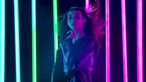 Portrait of a Young Pretty Woman with Hair Flying in the Wind Poses Against a Dark Studio Background