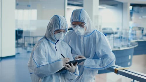 Scientists in Protective Suits Taking Notes in Lab