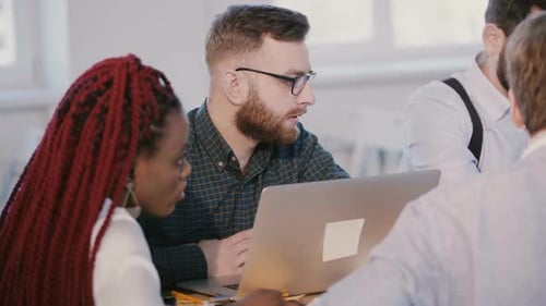 Diverse Team Collaborating on Laptop in Modern Office