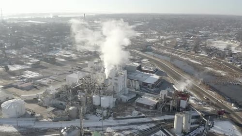 Slow aerial approach over city factory during winter day