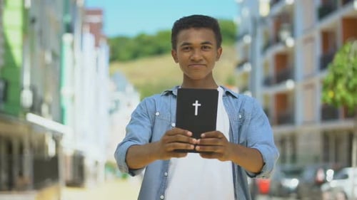 Teen Holding a Book With Cross Symbol