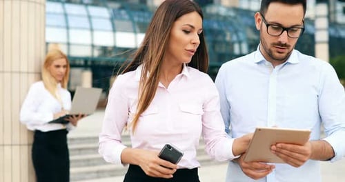 Business People Discussing Work on Tablet Outside Office