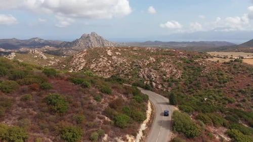 Aerial Shot of Electric Car Driving on the Sunny Desert Clean Road Highway to Mountains Landscape