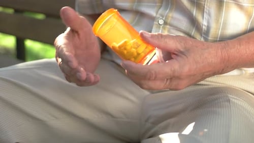 Senior Man Opening Pill Bottle on Park Bench