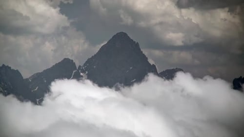 8K Rocky Sharp Mountain Peak Above the Clouds