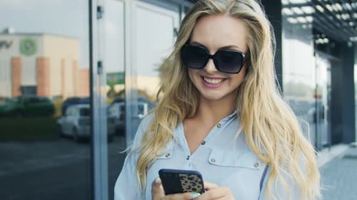 Smiling Woman Using Phone Outside Office Building