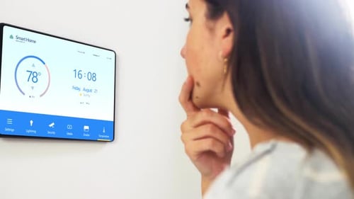 Woman Looks at Smart Home Device on Wall
