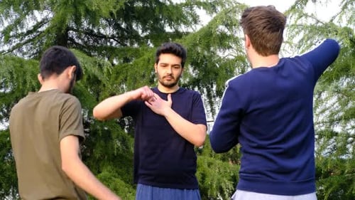 Young Adults Exercise Arms Together Outdoors